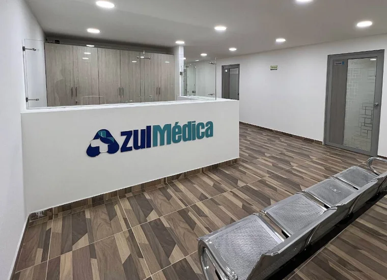 Recepción de Azul Médica: el mostrador con el logo en el frente y la sala de espera con sillas